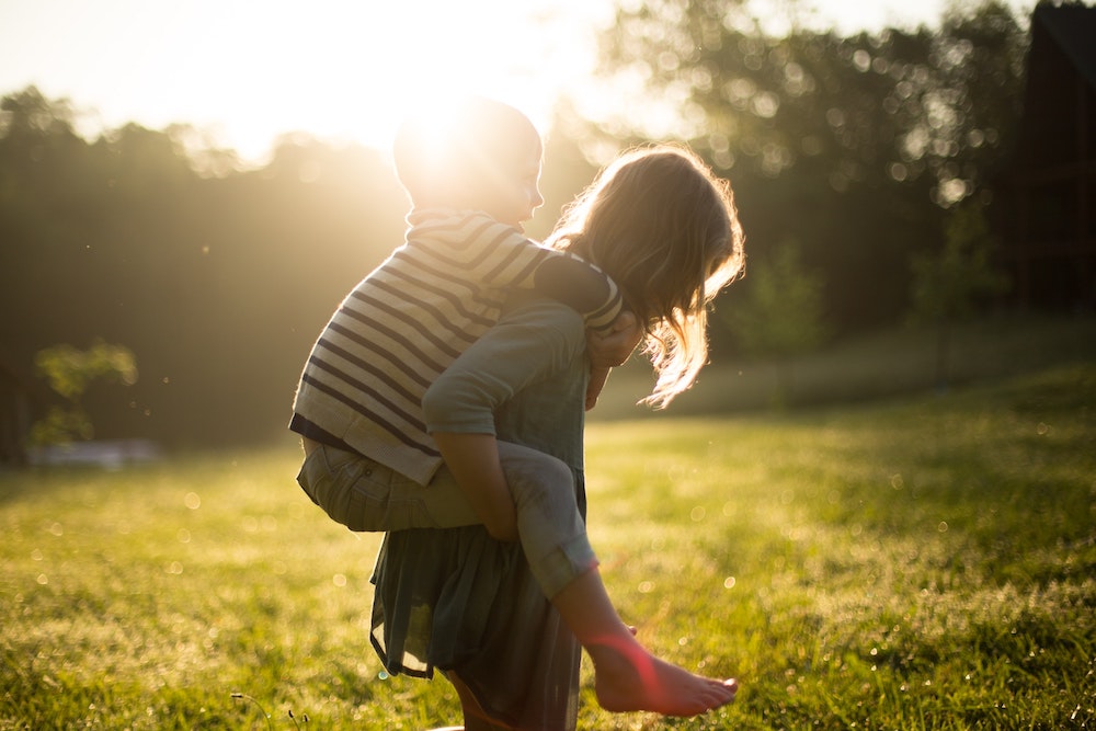 little girl giving little boy piggy back ride