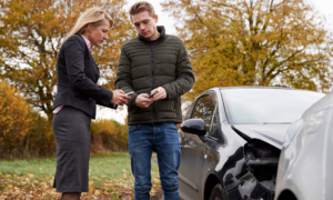 Picture of drivers exchanging insurance after an accident. Each diver should have uninsured motorist coverage. 