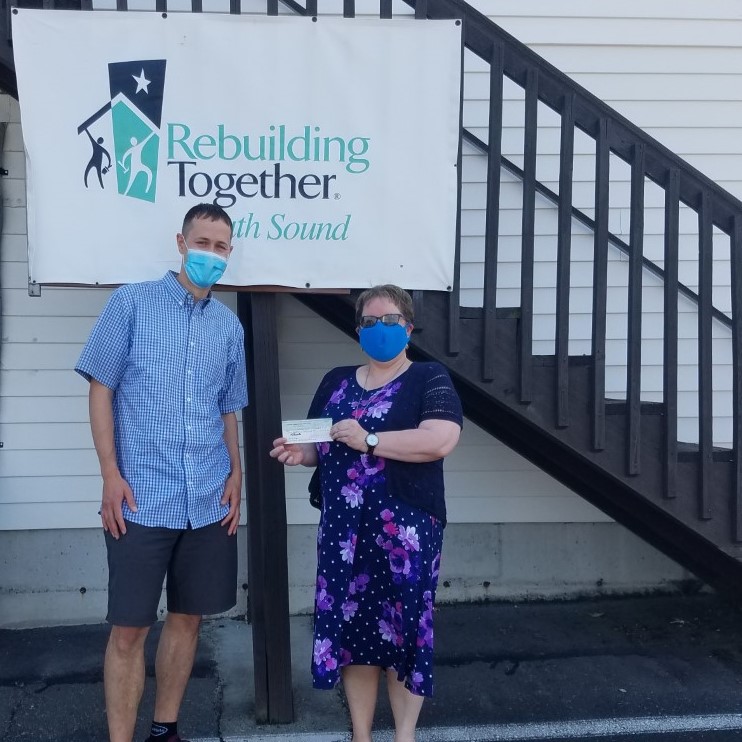 Ryan Stueber from PNW Insurance Group dropping off donation check to RebuildingTogether South Sound