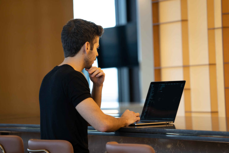 person sitting on desk looking at laptop